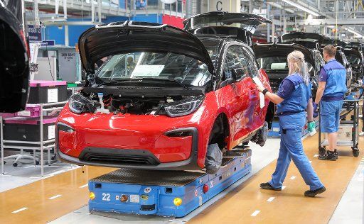 20 May 2019, Saxony, Leipzig: Employees at the BMW plant in Leipzig work on the assembly of the i3. The plug-in hybrid has been built at BMW\