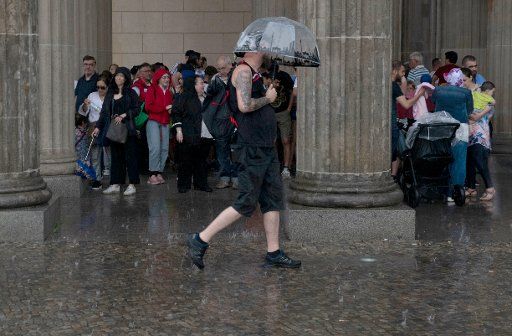 06 June 2019, Berlin: Tourists seek shelter from the rain at Pariser Platz. Photo: Paul Zinken\/