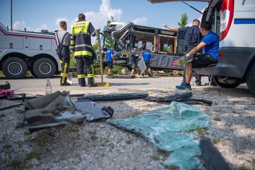 27 June 2019, Bavaria, Neuötting: A fireman stands in front of a school bus completely destroyed by an accident next to parts of the accident. 27 people were injured in a collision between a school bus and a truck in Neuötting, Upper Bavaria - one person seriously. Photo: Lino Mirgeler\/