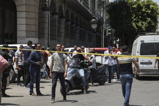 27 June 2019, Tunisia, Tunis: People stand behind a police barricade tape cordoning off the scene where a person blew himself up near a police patrol car injuring five people, at the Charles de Gaulle Avenue. Photo: Khaled Nasraoui\/