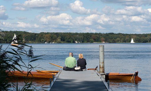 A woman and a man sit together on a pier at the Wannsee lake in Berlin, Germany, 28 August 2017. Photo: Paul Zinken\/