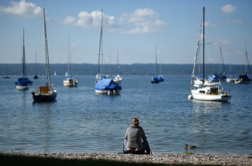 A woman sits at the shore of the Ammersee lake during sunny weather in Herrsching, Germany, 21 September 2017. Photo: Andreas Gebert\/