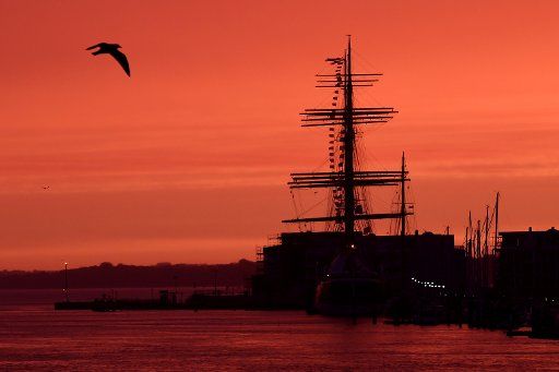 The sky appears red during sunrise above the 4 mast passat ship in Travemuende, Germany, 03 October 2017. Photo: Maurizio Gambarini\/