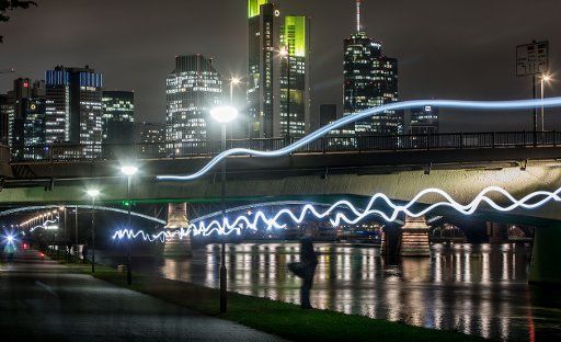 Joggers wearing headlamps leave a trail of light along the banks of the river Main in Frankfurt, Germany, 10 October 2017. (Bulb exposure photograph.) Photo: Frank Rumpenhorst\/