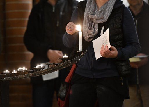 dpatop - A woman lighting a candle during a prayer for human rights activists and journalists imprisoned in Turkey, among them Peter Steudtner, in the Gethsemane Church in Berlin, Germany, 25 October 2017. Photo: Paul Zinken\/