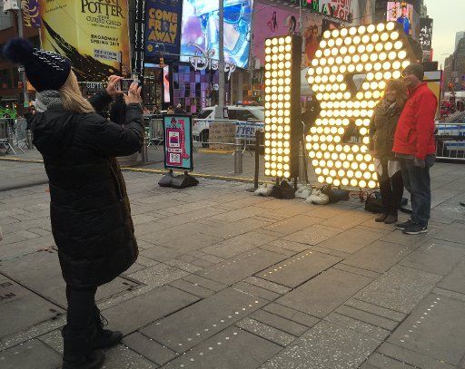 People taking pictures next to the numbers 1 and 8, made out of dozens of light bulbs, in Times Square in New York, US, 15 December 2017. Photo: Christina Horsten\/