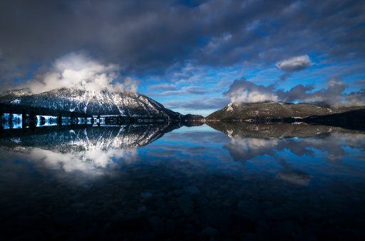 The Herzogstand mountain shines bright in the sunlight and is mirrored in the water of Lake Walchen near Einsiedl, Germany, 20 December 2017. Photo: Peter Kneffel\/