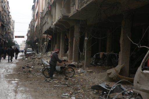 A man walks with his bike into the ruins of a building that destroyed by Syrian forces\