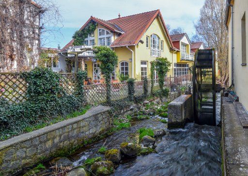 12 April 2018, Germany, Buckow: The water of Stobber stream runs underneath the fast spinning millwheel in the spa town of Buckow. Photo: Patrick Pleul\/dpa-Zentralbild\/