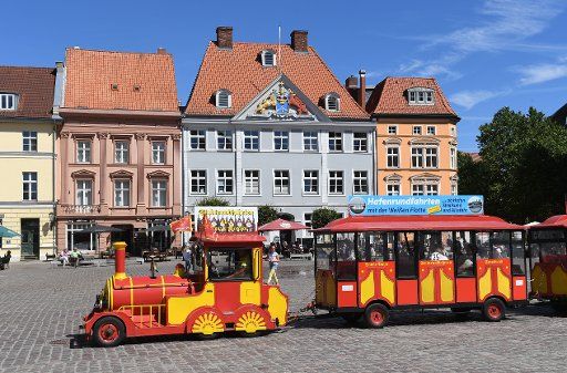 06 June 2018, Germany, Stralsund: The Hanse tram carrying tourists over the old market. Super weather has been making cash registers in gastronomy and hotels ring. Photo: Stefan Sauer\/