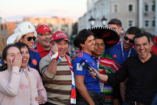 15 June 2018, Russia, Kazan: A South American reporter interviews soccer fans from Russia, Mexico and Colombia. Photo: Andreas Gebert\/