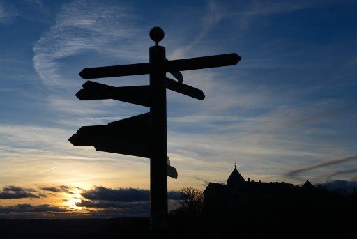 A signpost stands in front of castle Waldeck while the sun sets in Waldeck, Germany, 08 January 2014. Photo: Uwe Zucchi\/