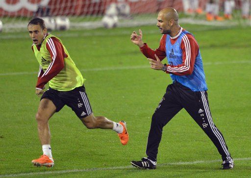 Head coach of Bundesliga soccer club Bayern Munich, Pep Guardiola (R), issues instructions to player Rafinha during a training session in Doha, Qatar, 06 January 2014. The team of Bayern Munich will prepare for the second leg of the 2013-14 ...