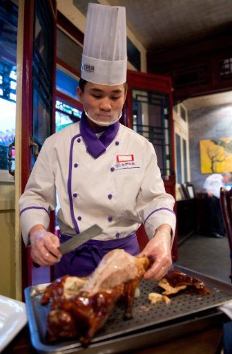 A chef carves a Peking duck in a restaurant in Beijing, China, 14 April 2014. Photo: Tim Brakemeier\/