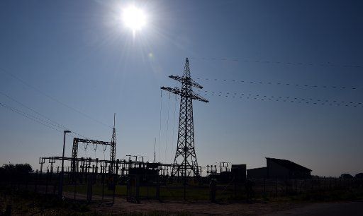 A power pole silhouettes against the sun at the electrical substation of the Schleswig-Holstein Netz AG company in Struebbel, Germany, 20 May 2014. Photo: Carsten Rehder\/