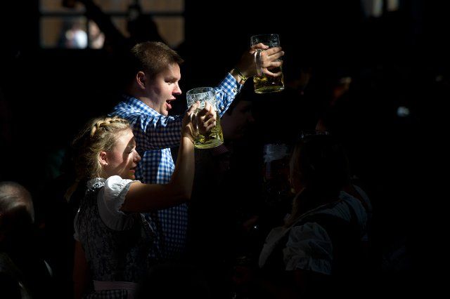 Two visitors lift their tankards illuminated by a ray of sunlight at the Oktoberfest 2014 in Munich (Bavaria), Germany, 28 September 2014. PHOTO: TOBIAS HASE\/