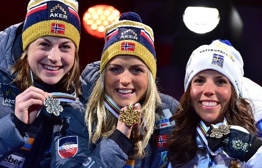 Winner Therese Johaug of Norway (C), second placed Astrid Uhrenholdt Jacobsen (L) of Norway and third placed Charlotte Kalla of Sweden celebrate during the medal ceremony after the women\