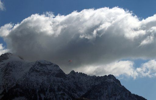 A paraglider floats over some snow-covered mountains of the Alps near Buching, Germany, 7 April 2015. Photo: Karl-Josef Hildenbrand\/