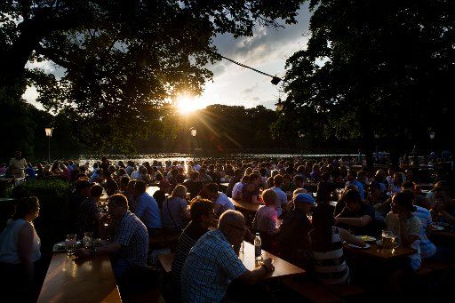 People enjoy the evening sun as they sit in an open-air pub in Munich, Germany, 13 June 2015. Photo: Tobias Hase\/