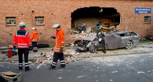 Task forces stand in front of a car wreck at the crash site in Haenigsen, Germany, 07 June 2015. Three people died when a car caught a pedestrian with excessive speed before it plowed into a house wall in the evening. The pedstrian as well as the ...