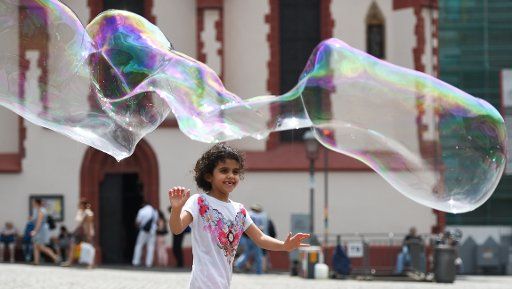 A girl chases after a giant soap bubble at the Roemerberg in Frankfurt am Main, Germany, 24 July 2015. Photo: Arne Dedert\/