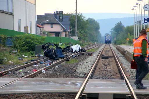 The wreck of a car on the tracks near a railway crossing in Monzingen, Germany, 12 September 2015. In the background is the train that hit the car. Five young men aged 17 - 21 died Saturday, when a train hit a car which was on the crossing. PHOTO: ...