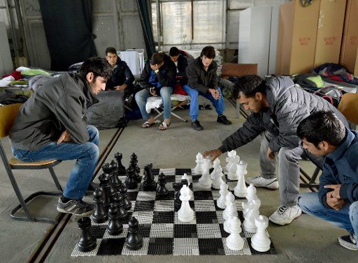Refugees from Afghanistan play chess in an emergency shelter in Eisenhuettenstadt, Germany, 17 October 2015. 17 winterproof halls for some 1,000 refugees will be erected on the former grounds of the German federal police. Photo: Bernd Settnik\/