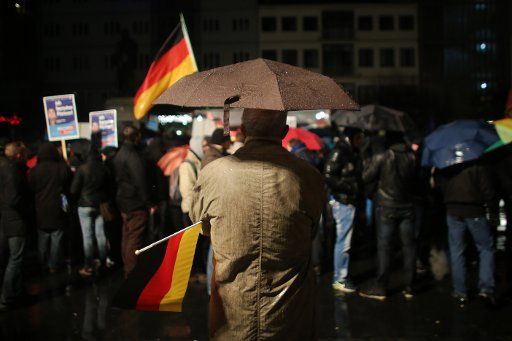 A supporter of the "Alternative für Deutschland" party with a German flag and umbrella at Gutenbergplatz in Mainz, Germany, 21 November 2015. AfD called a demonstration in Mainz under the slogan "Gegen das Asylchaos" (lit. against the asylum chaos). ...