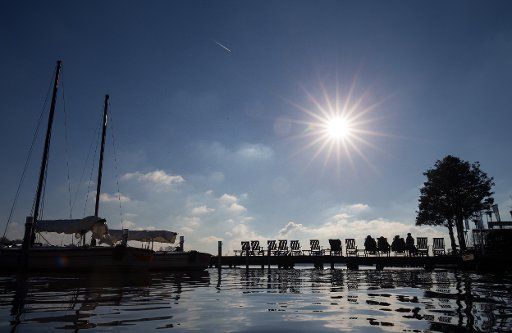 Customers at a cafe sitting in bright sunshine and frosty temperatures on a jetty by the river Alster in Hamburg, Germany, 16 February 2016. PHOTO: CHRISTIAN CHARISIUS\/