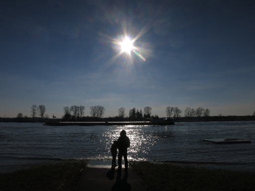 A man and a child are lit by the spring sun at the Rhine riverbank in Bonn, Germany, 27 February 2016. Photo: OLIVER BERG\/
