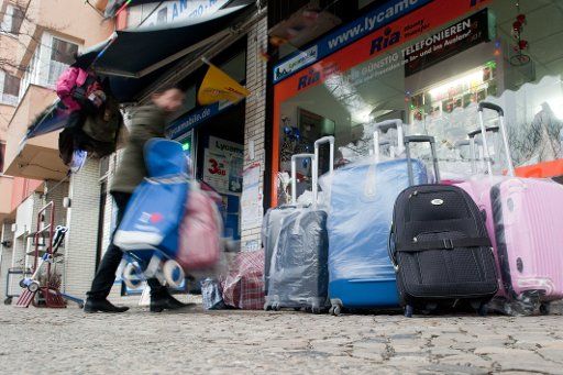 A trader carrying suitcases in front of his shop in Berlin-Moabit, Germany, 8 February 2016. Photo: Klaus-Dietmar Gabbert\/