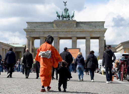 A Japanese woman wearing a kimono stands with her son in front of the Brandenburg Gate in Berlin, Germany, 25 April 2016. Photo: BRITTA PEDERSEN\/