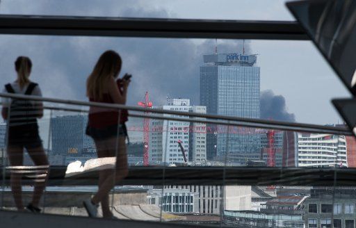 A huge smoke cloud bellows from the Dong Xuan Center in Berlin, Germany, 11 May 2016. In the foreground vistors to the German Reichstag dome can be seen. On the site of the Asian shopping center in Berlin-Lichtenberg a warehouse fire broke out on ...