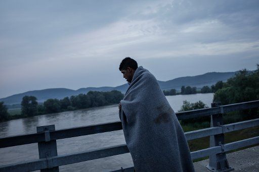 A man covered by a blanket crosses a bridge near Idomeni, Greece, 24 May 2016. Photo: Socrates Baltagiannis\/