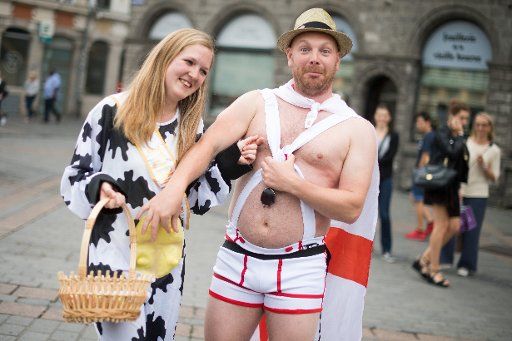 A supporter of the English team jokes with a bachelorette in a cow costume in Lille, France, 11 June 2016. The UEFA EURO 2016 takes place from 10 June to 10 July 2016 in France. Photo: Marius Becker\/