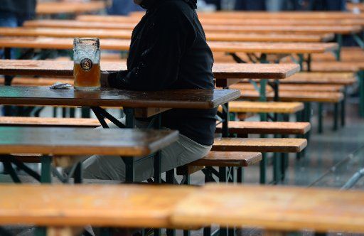 A man sits on a beer table in rainy weather at the Munich City Foundation Festival at the Marienplatz in Munich, Germany, 19 June 2016. Photo: ANDREAS GEBERT\/