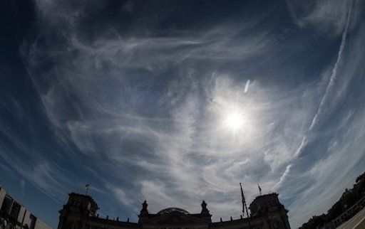The sun shining through the clouds above the Reichstag building in Berlin, Germany, 22 July 2016. PHOTO: PAUL ZINKEN\/