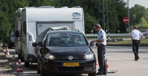 A police officer inspects a car with a camper trailer by the A5 highway near Neuenburg, Germany, 22 July 2016. Because many campers and trailers are overloaded during summer, the Police are toughening checks across Germany. Photo: Patrick Seeger\/