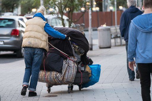 A homeless woman pushes a trolley with her personal belongings in Hannover, Germany, 15 July 2016. Photo: Peter Steffen\/