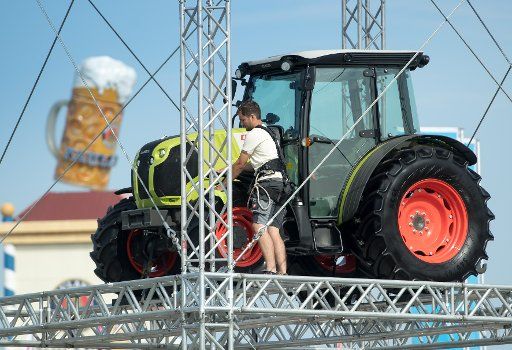 A man puts the finishing touches on a tractor on a tall scaffolding during the press tour of the Bavarian Central Agriculture Festival (ZLF) on the Oktoberfest grounds in Munich, Germany, 16 September 2016. An over-sized beer mug can be seen in the ...