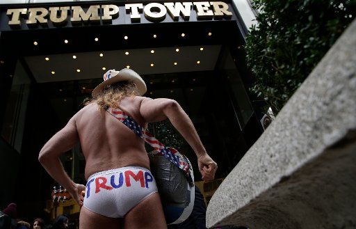 An American street musician known as Naked Cowboy plays guitar outside at the entrance to Trump Tower on December 11, 2016 in New York City. U.S. President-elect Donald Trump is still holding meetings upstairs at Trump Tower as he continues to fill ...