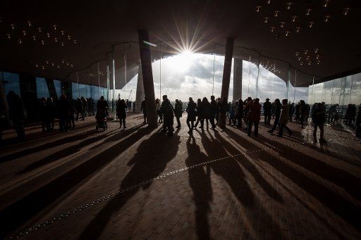 Numerous visitors walk across the plaza at the Elbphilharmonie and cast long shadows on the ground in Hamburg, Germany, 26 December 2016. Photo: Christian Charisius\/