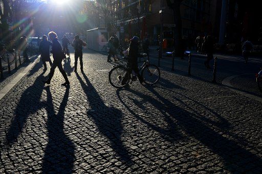 Passer-bys cast long shadows at the Postdamer Plaza in Berlin, Germany, 14 February 2017. Photo: Maurizio Gambarini\/