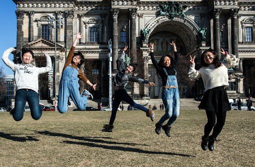Five young Chinese women jump in the sun in front of the Berlin Cathedral in Berlin, Germany, 15 February 2017. Photo: Paul Zinken\/