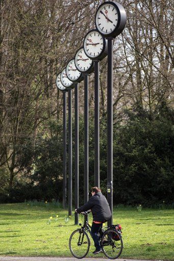 A cyclist rides past an installation ("Time field") by the artist Klaus Rinke in Duesseldorf, Germany, 24 March 2017. In the night on Sunday, the clocks will be set forward to summer time - from 2:00 to 3:00am. Photo: Federico Gambarini\/