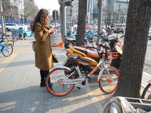 A woman stands in front of a bicycle of the rental bike company \