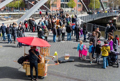 People watch a street musician perform next to the Niederbaumbruecke bridge in Hamburg, Germany, 16 April 2017. Photo: Christophe Gateau\/