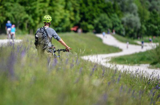 A cyclist pushes his bike at the Isar River in Munich, Germany, 27 May 2017. Photo: Matthias Balk\/