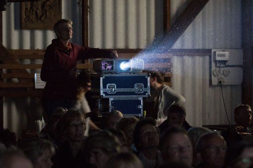 Ulrike Meinert of the mobile cinema stands behind the projector inside a barn for a movie screening in Wueppels, Germany, 23 July 2017. Photo: Mohssen Assanimoghaddam\/