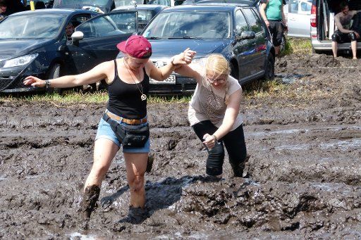 Visitors walking through the mud in Weeze, Germany, 24 July 2017. After heavy rain at the Parookaville electronic music festival in Weeze farmers helped campers to get their cars out of the mud on Monday. Photo: Manuel Funda\/